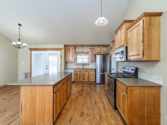 kitchen featuring stainless steel appliances, decorative light fixtures, dark wood finished floors, and a sink