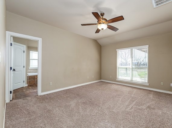 spare room with vaulted ceiling, carpet flooring, visible vents, and baseboards