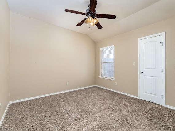 carpeted empty room with lofted ceiling, ceiling fan, and baseboards