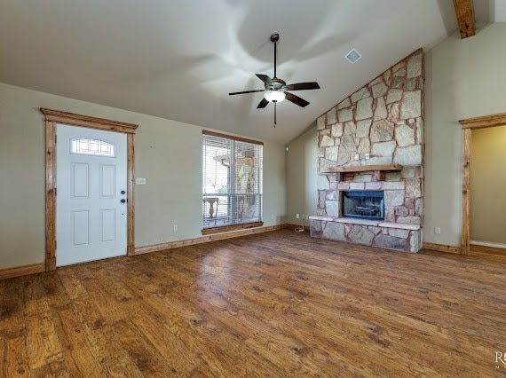 unfurnished living room featuring ceiling fan, a stone fireplace, wood finished floors, and visible vents