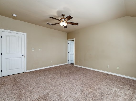 empty room featuring visible vents, baseboards, a ceiling fan, lofted ceiling, and carpet