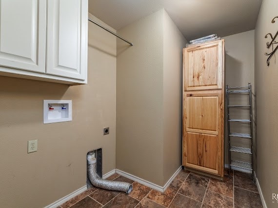 laundry room featuring cabinet space, baseboards, hookup for a washing machine, stone finish flooring, and electric dryer hookup