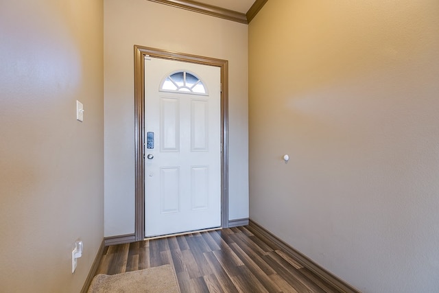 foyer with dark wood-type flooring, crown molding, and baseboards