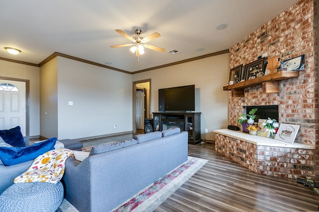 living area with a fireplace, visible vents, ceiling fan, wood finished floors, and baseboards