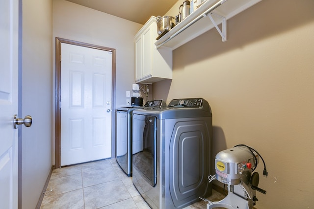 laundry area featuring cabinet space, washing machine and dryer, light tile patterned floors, and baseboards