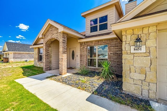 entrance to property featuring a yard and brick siding