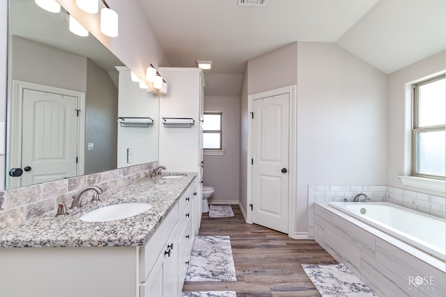 bathroom featuring visible vents, toilet, a garden tub, wood finished floors, and a sink