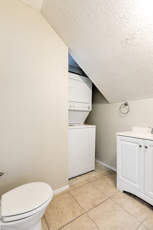 bathroom with stacked washer and dryer, baseboards, lofted ceiling, and a textured ceiling