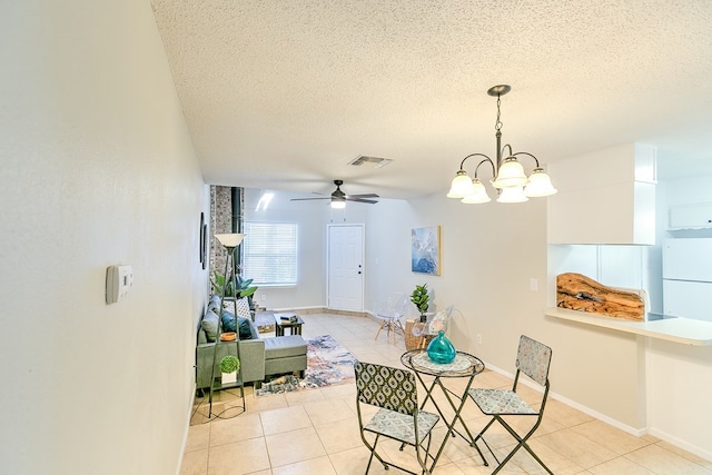 dining space featuring light tile patterned floors, ceiling fan with notable chandelier, visible vents, and a textured ceiling
