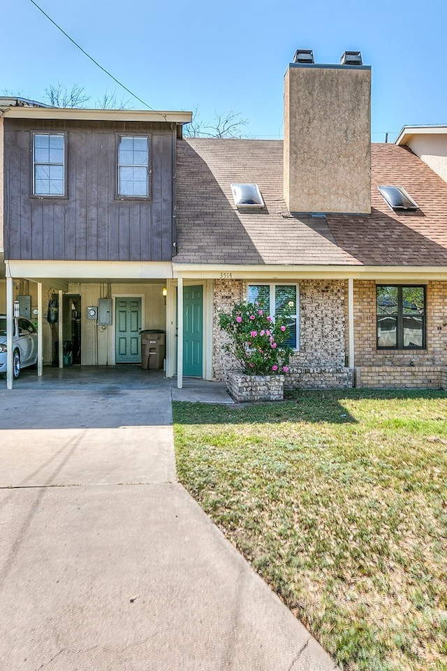 view of front of house featuring a carport, a shingled roof, a front lawn, a chimney, and concrete driveway