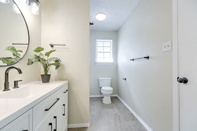 half bath with toilet, a textured ceiling, vanity, and baseboards