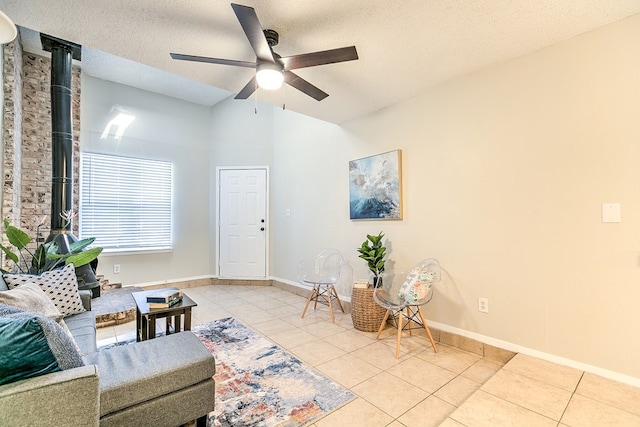 living area featuring a ceiling fan, a textured ceiling, baseboards, and tile patterned flooring