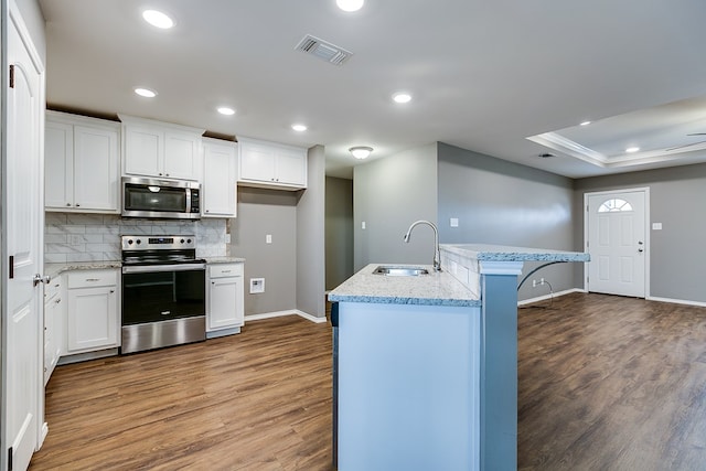 kitchen featuring an island with sink, hardwood / wood-style flooring, appliances with stainless steel finishes, and white cabinets