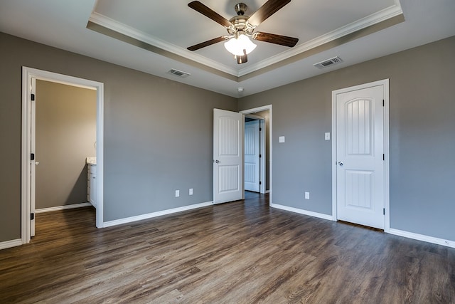 unfurnished bedroom featuring dark hardwood / wood-style flooring, crown molding, and a raised ceiling