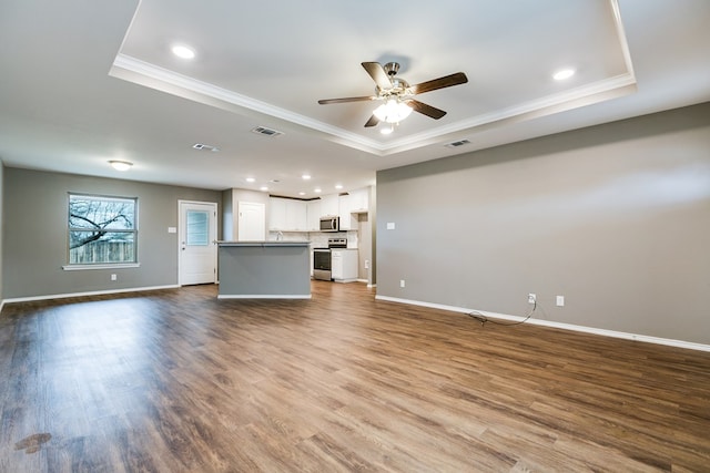 unfurnished living room with crown molding, wood-type flooring, and a raised ceiling