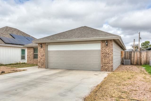 view of front of house featuring central air condition unit, solar panels, and a garage