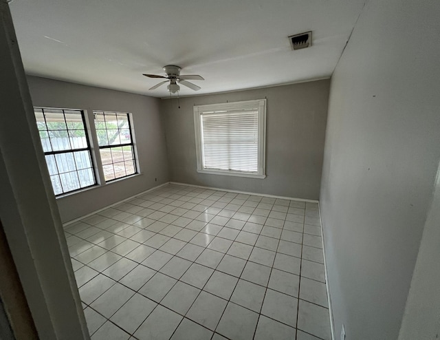 unfurnished room with light tile patterned floors, ceiling fan, visible vents, and baseboards