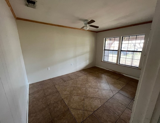 empty room featuring ornamental molding, dark tile patterned flooring, visible vents, and ceiling fan