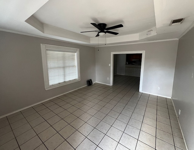 empty room with visible vents, a tray ceiling, ceiling fan, and ornamental molding