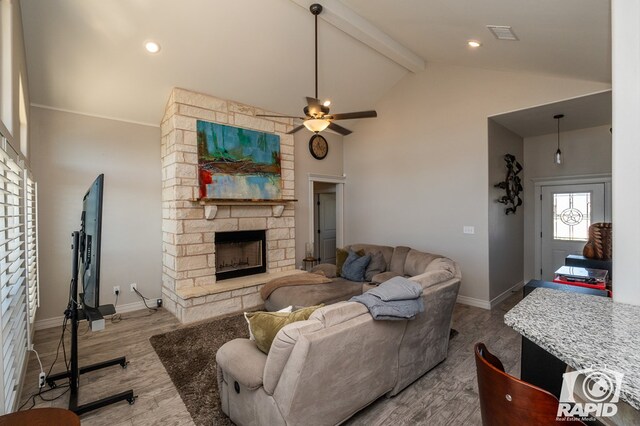 living room featuring beam ceiling, high vaulted ceiling, light wood-type flooring, ceiling fan, and a fireplace