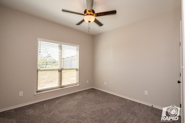 empty room featuring ceiling fan and dark colored carpet