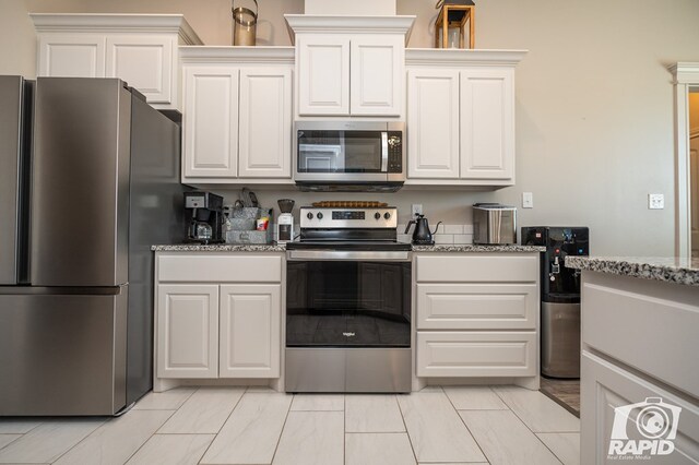 kitchen featuring light stone countertops, appliances with stainless steel finishes, and white cabinets