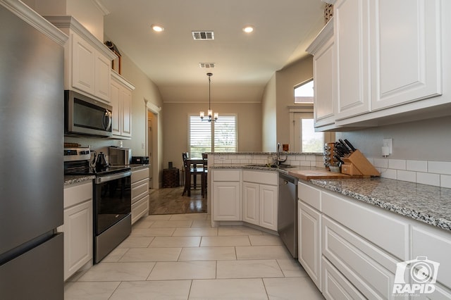 kitchen with appliances with stainless steel finishes, sink, white cabinets, and an inviting chandelier