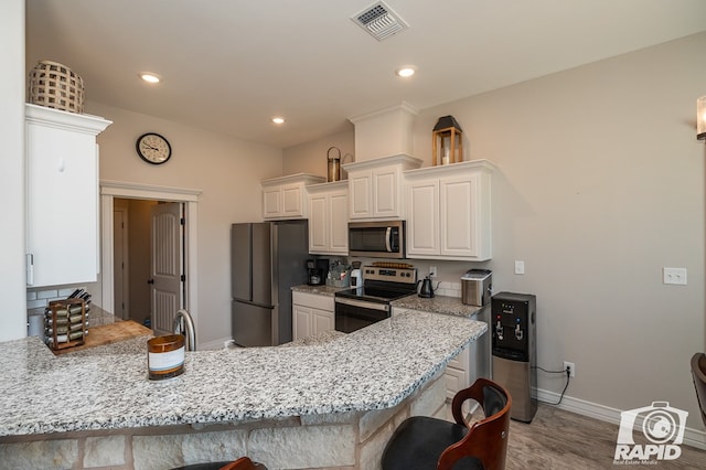 kitchen with a breakfast bar area, white cabinetry, light wood-type flooring, appliances with stainless steel finishes, and kitchen peninsula