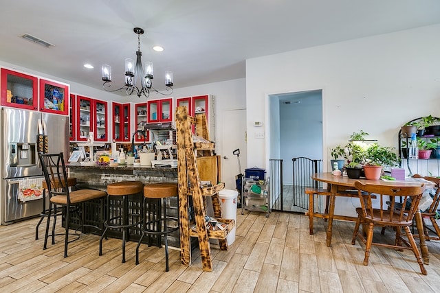 bar featuring stainless steel refrigerator with ice dispenser, a chandelier, light hardwood / wood-style floors, and decorative light fixtures