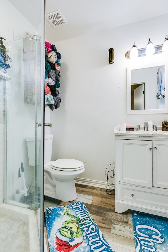 bathroom featuring hardwood / wood-style flooring, vanity, a shower with door, and toilet