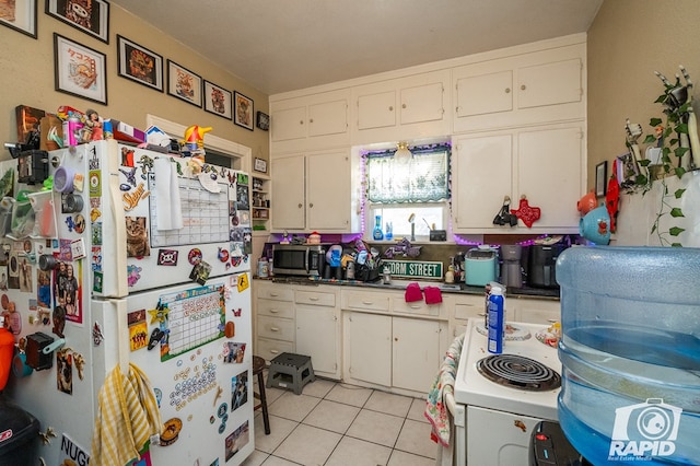 kitchen featuring light tile patterned floors, white cabinets, and white appliances