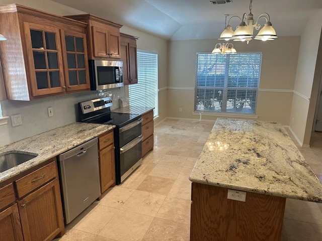 kitchen featuring a center island, a chandelier, vaulted ceiling, pendant lighting, and stainless steel appliances