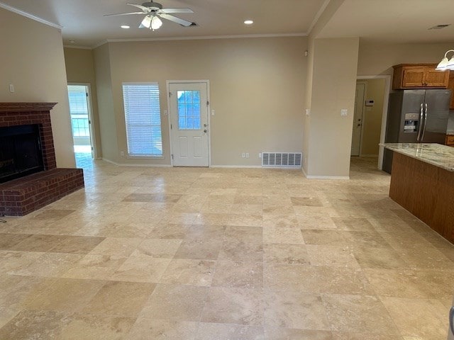 unfurnished living room featuring crown molding, ceiling fan, and a fireplace