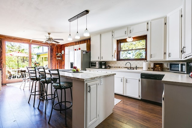 kitchen featuring sink, white cabinetry, decorative light fixtures, appliances with stainless steel finishes, and a kitchen island