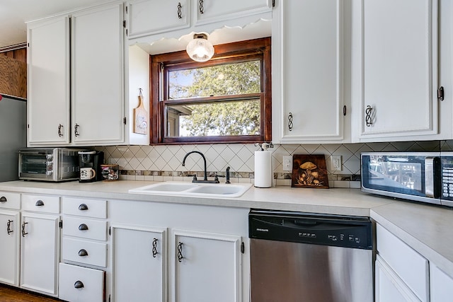 kitchen with white cabinetry, appliances with stainless steel finishes, sink, and backsplash