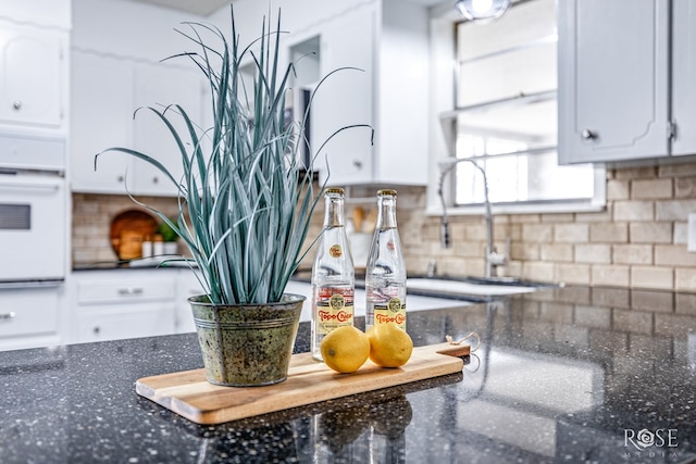 3102 Chatterton Dr, San Angelo, TX 76904 - details with backsplash, dark stone countertops, white cabinetry, and oven