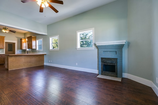 unfurnished living room featuring dark hardwood / wood-style floors, ceiling fan, a fireplace, and sink