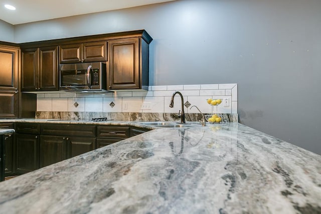 1001 Avondale Ave, San Angelo, TX 76901 - kitchen with stainless steel microwave, black electric stovetop, a sink, tasteful backsplash, and recessed lighting