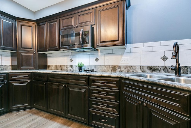 1001 Avondale Ave, San Angelo, TX 76901 - kitchen featuring stainless steel microwave, a sink, black electric cooktop, backsplash, and light wood finished floors
