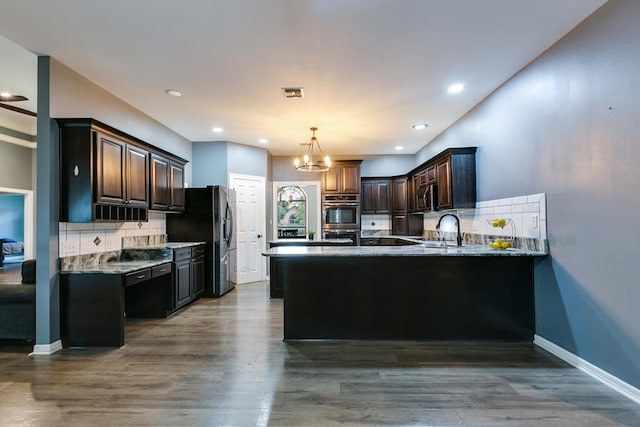 1001 Avondale Ave, San Angelo, TX 76901 - kitchen with stainless steel double oven, tasteful backsplash, dark brown cabinets, a peninsula, and light stone countertops