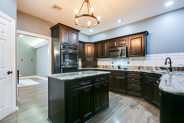 1001 Avondale Ave, San Angelo, TX 76901 - kitchen with a sink, appliances with stainless steel finishes, a chandelier, light wood-style flooring, and decorative backsplash