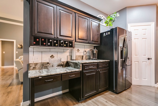 1001 Avondale Ave, San Angelo, TX 76901 - kitchen featuring decorative backsplash, stainless steel refrigerator with ice dispenser, dark brown cabinetry, light wood finished floors, and light stone countertops