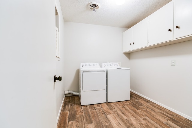 laundry area with cabinets, washer and dryer, dark wood-type flooring, and a textured ceiling