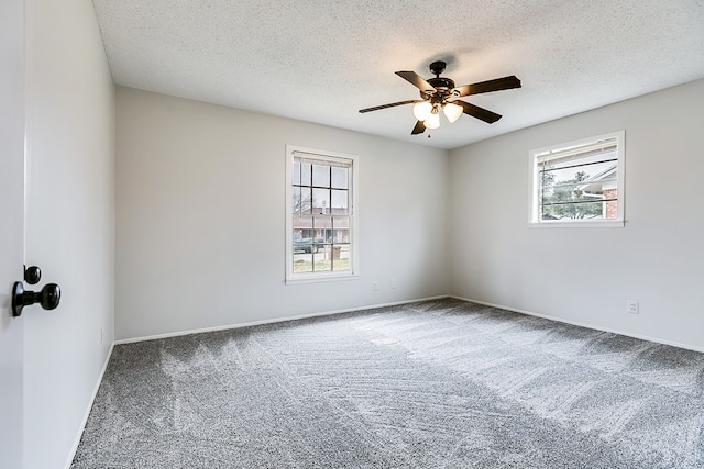 carpeted spare room with a textured ceiling, ceiling fan, and a wealth of natural light