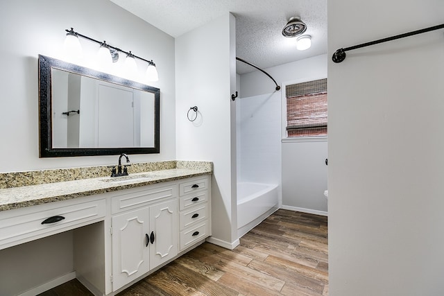 bathroom featuring shower / bathing tub combination, wood-type flooring, vanity, and a textured ceiling