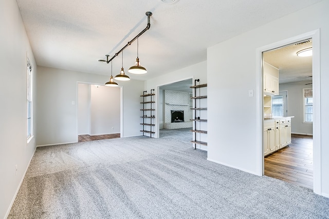 unfurnished living room featuring a fireplace, light carpet, and a textured ceiling