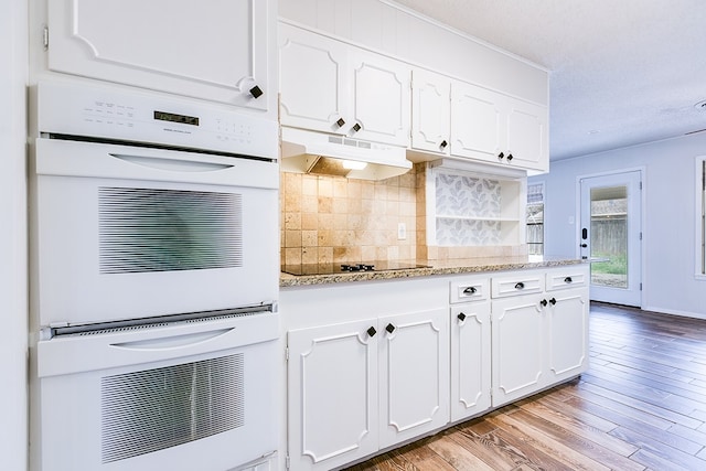 kitchen with black electric cooktop, light stone counters, and white cabinets