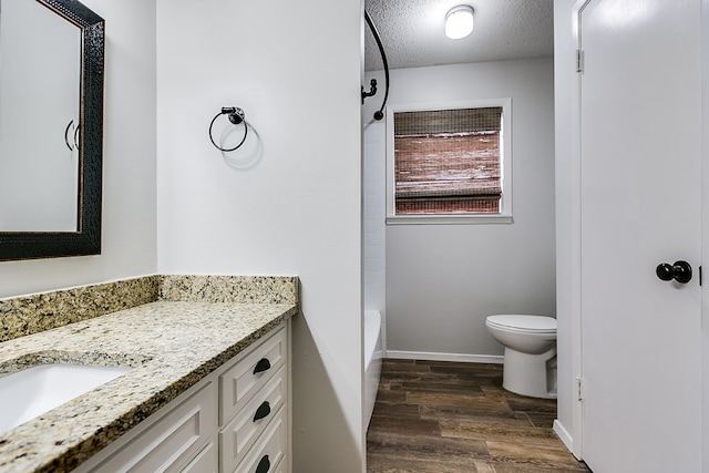 full bathroom with vanity, a textured ceiling, toilet, hardwood / wood-style flooring, and  shower combination