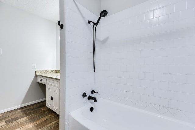 bathroom with hardwood / wood-style flooring, vanity, and tiled shower / bath combo