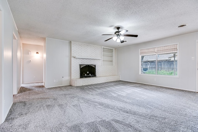 unfurnished living room with a fireplace, ceiling fan, carpet floors, and a textured ceiling